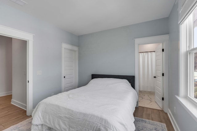 bedroom with baseboards, multiple windows, and wood finished floors