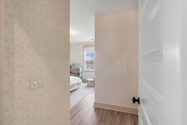 hallway with wallpapered walls, baseboards, and wood finished floors