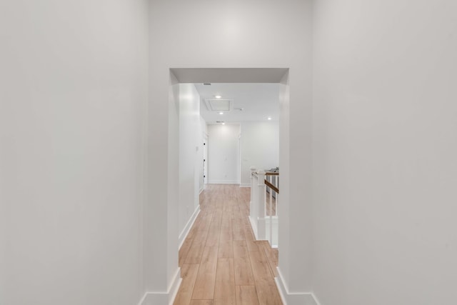 hallway featuring light wood-style flooring, an upstairs landing, and baseboards