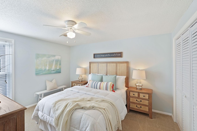 bedroom with a closet, light colored carpet, a ceiling fan, and baseboards