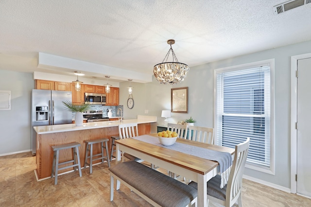 dining room featuring visible vents, baseboards, a textured ceiling, and an inviting chandelier