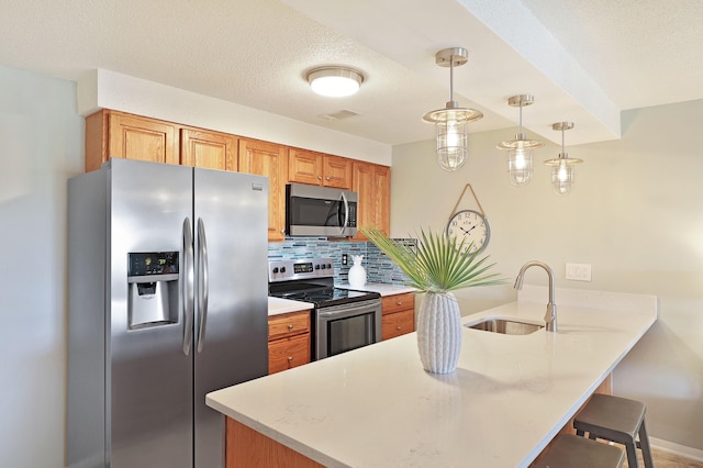 kitchen with a breakfast bar area, a peninsula, a sink, decorative backsplash, and appliances with stainless steel finishes