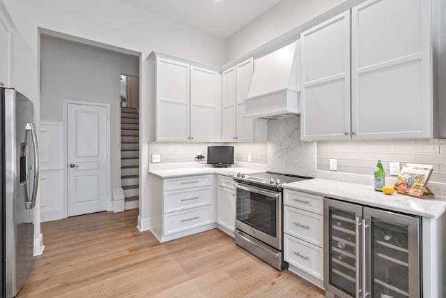 116 Cartright St, Daniel Island, SC 29492 - kitchen featuring appliances with stainless steel finishes, custom exhaust hood, beverage cooler, white cabinets, and light wood-type flooring