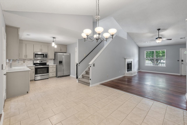unfurnished living room featuring lofted ceiling, light tile patterned floors, a ceiling fan, a fireplace with raised hearth, and baseboards