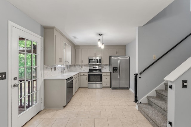 kitchen featuring appliances with stainless steel finishes, a sink, gray cabinets, and light countertops