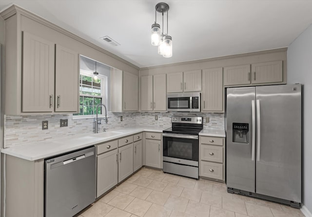 kitchen with stainless steel appliances, a sink, gray cabinets, decorative backsplash, and light countertops