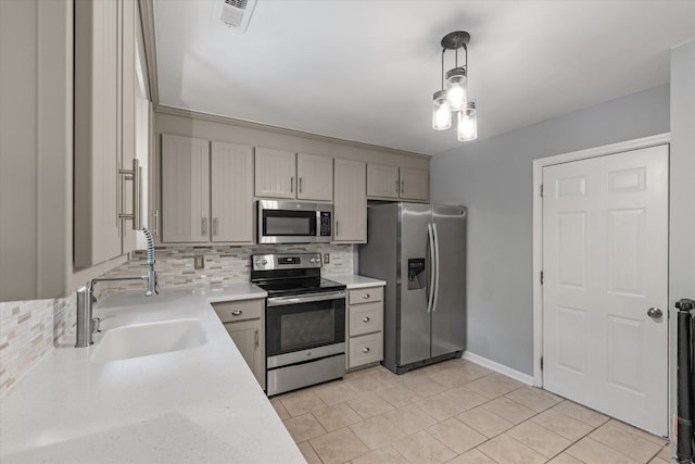 kitchen with stainless steel appliances, decorative backsplash, gray cabinets, a sink, and hanging light fixtures
