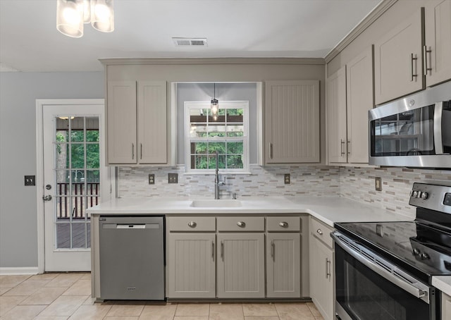 kitchen with stainless steel appliances, a sink, gray cabinets, and healthy amount of natural light