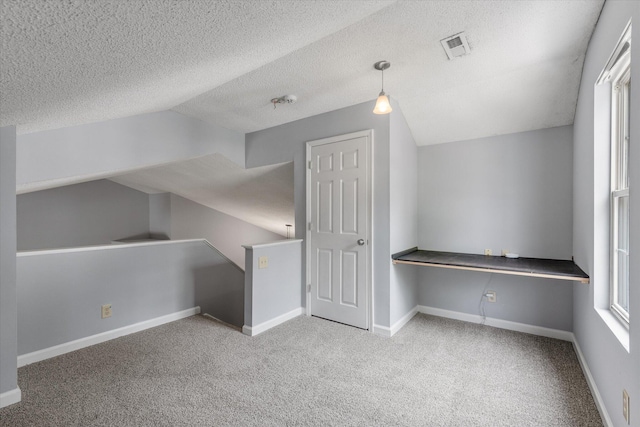 additional living space featuring vaulted ceiling, carpet, a textured ceiling, and baseboards