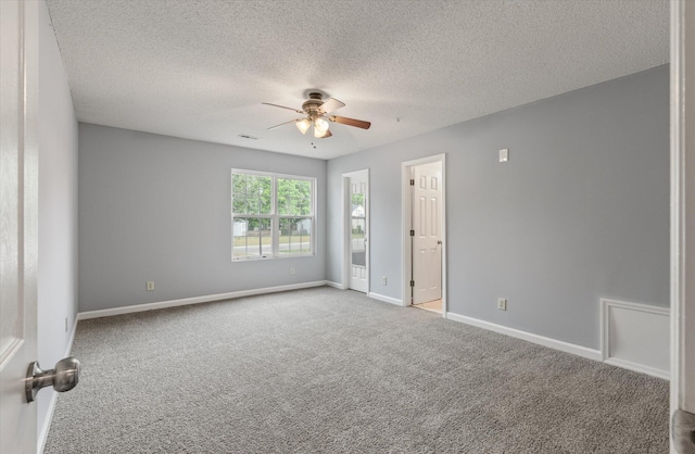 spare room with a ceiling fan, carpet flooring, baseboards, and a textured ceiling