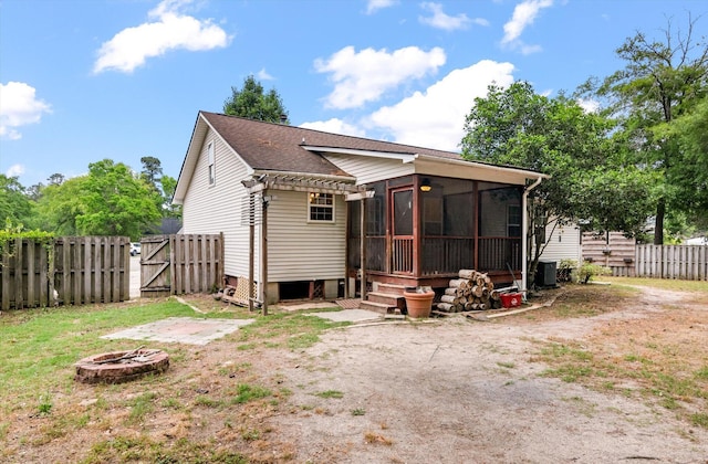 rear view of house with an outdoor fire pit, a sunroom, a gate, fence, and central air condition unit