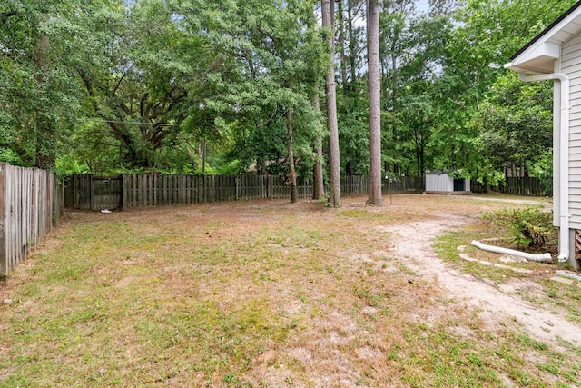 view of yard with a storage unit, an outbuilding, and view of wooded area