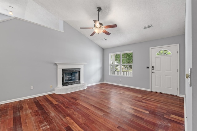 unfurnished living room featuring a ceiling fan, wood finished floors, a brick fireplace, a textured ceiling, and baseboards