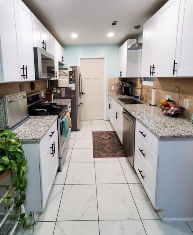 kitchen with white cabinets, appliances with stainless steel finishes, light stone counters, and sink