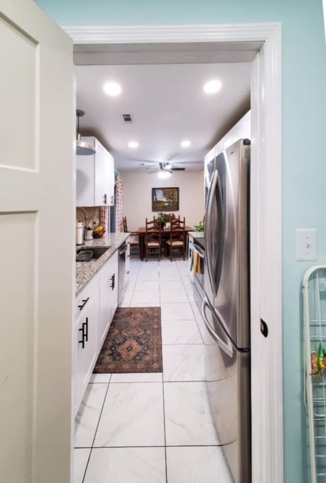 kitchen with sink, ceiling fan, light stone counters, white cabinetry, and stainless steel appliances