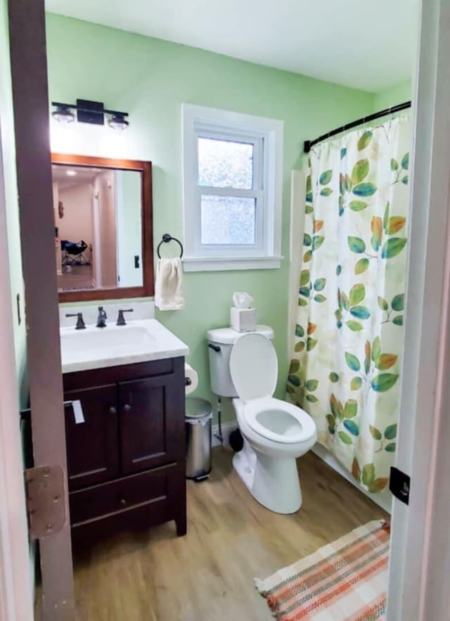 bathroom with a shower with curtain, toilet, vanity, and hardwood / wood-style flooring