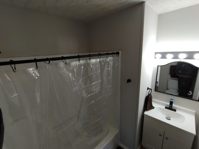 full bath featuring vanity, toilet, and a textured ceiling