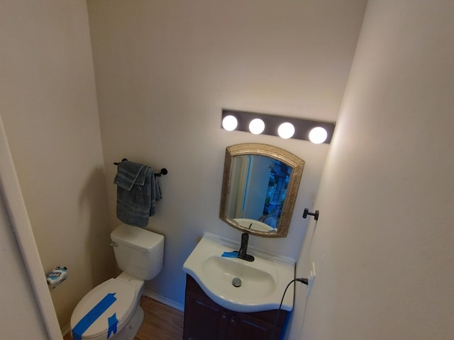 half bath featuring toilet, vanity, and baseboards