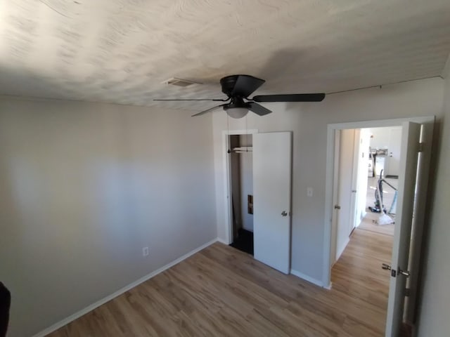 unfurnished bedroom with light wood finished floors, baseboards, a closet, and a ceiling fan