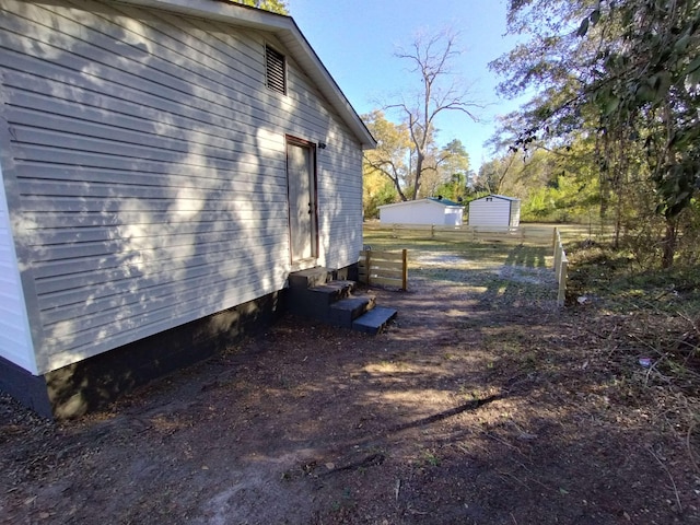 view of side of home with entry steps and fence