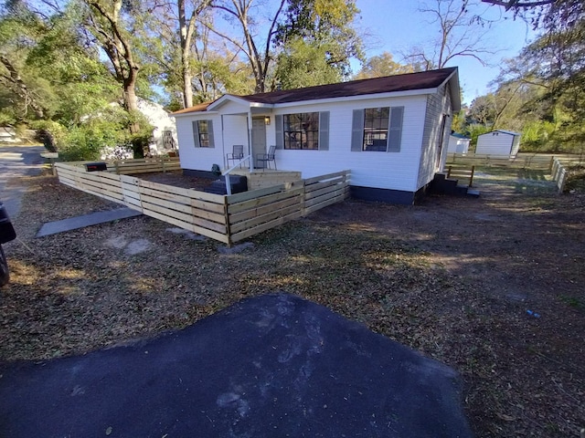 view of front of home featuring fence and an outbuilding