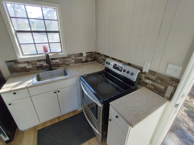kitchen featuring stainless steel electric range oven, a sink, decorative backsplash, and light countertops