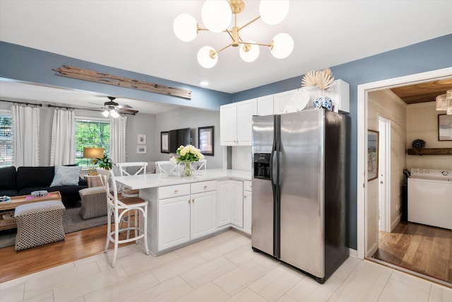 520 Yale Dr, Charleston, SC 29412 - kitchen with stainless steel fridge, washer / clothes dryer, a peninsula, a chandelier, and white cabinets