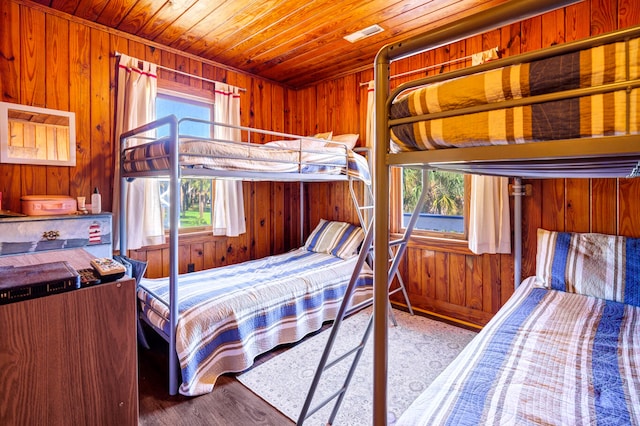 bedroom with wood walls, wood-type flooring, wooden ceiling, and multiple windows