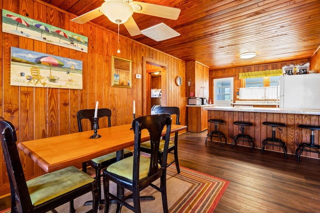 dining space with ceiling fan, dark hardwood / wood-style flooring, wooden ceiling, and wood walls