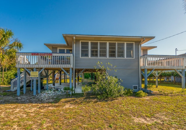 rear view of house featuring a lawn, a patio area, and a wooden deck