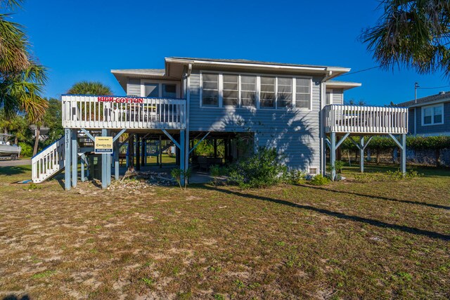 rear view of property featuring a wooden deck and a yard