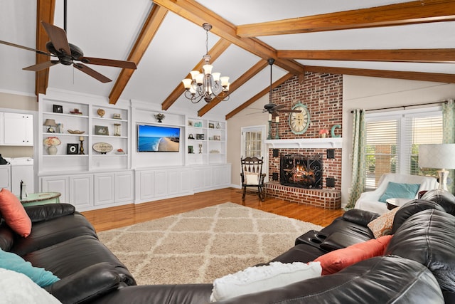 living room featuring light wood-type flooring, ceiling fan with notable chandelier, separate washer and dryer, vaulted ceiling with beams, and a brick fireplace