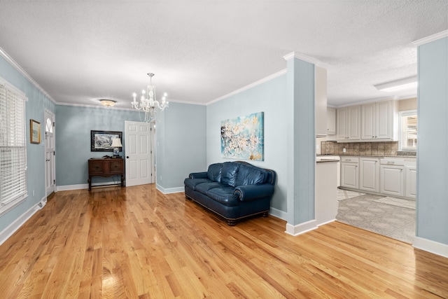 unfurnished room featuring light hardwood / wood-style flooring, ornamental molding, a textured ceiling, and a notable chandelier