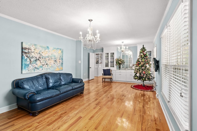 living room with crown molding, a textured ceiling, a chandelier, and hardwood / wood-style floors