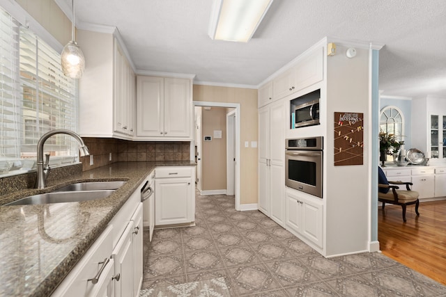 kitchen with white cabinetry, dark stone counters, sink, decorative light fixtures, and stainless steel appliances