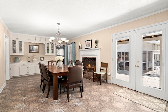 dining area featuring french doors, crown molding, and an inviting chandelier