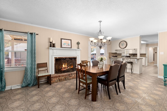 dining room with a notable chandelier, crown molding, a brick fireplace, and plenty of natural light