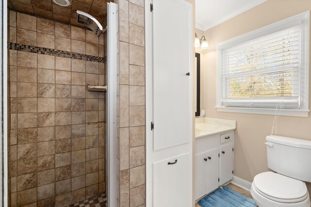 bathroom featuring vanity, toilet, crown molding, and tiled shower