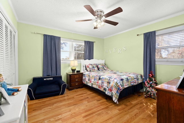 bedroom featuring a closet, crown molding, light wood-type flooring, a textured ceiling, and ceiling fan