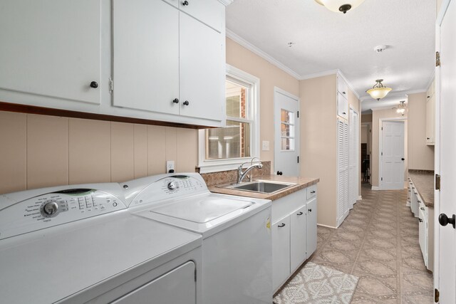 clothes washing area featuring cabinets, ornamental molding, sink, and washing machine and dryer