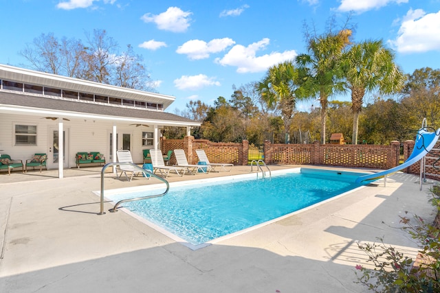 view of swimming pool featuring a water slide, a patio area, and ceiling fan