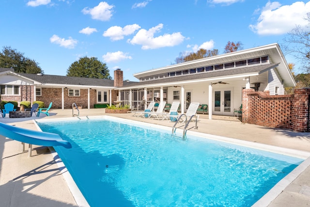 view of pool with a patio area, a water slide, french doors, and ceiling fan