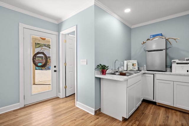 kitchen with light hardwood / wood-style floors, ornamental molding, sink, and white cabinets