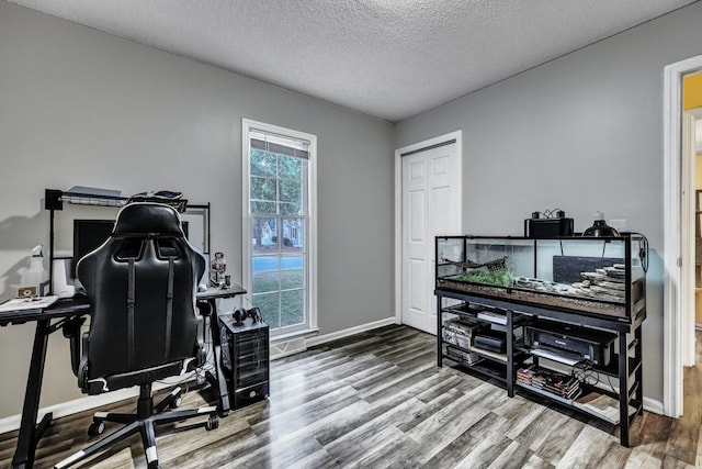 home office featuring a textured ceiling, wood finished floors, and baseboards