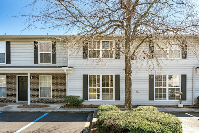 view of property featuring brick siding and uncovered parking