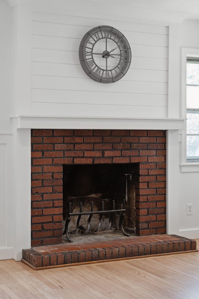 details featuring a brick fireplace and wood finished floors