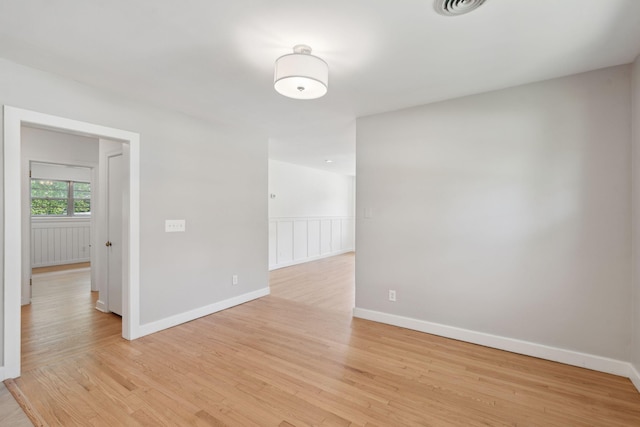 empty room with visible vents, light wood finished floors, and baseboards