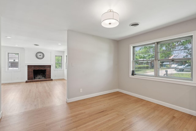 unfurnished living room featuring baseboards, a fireplace, light wood-type flooring, and visible vents