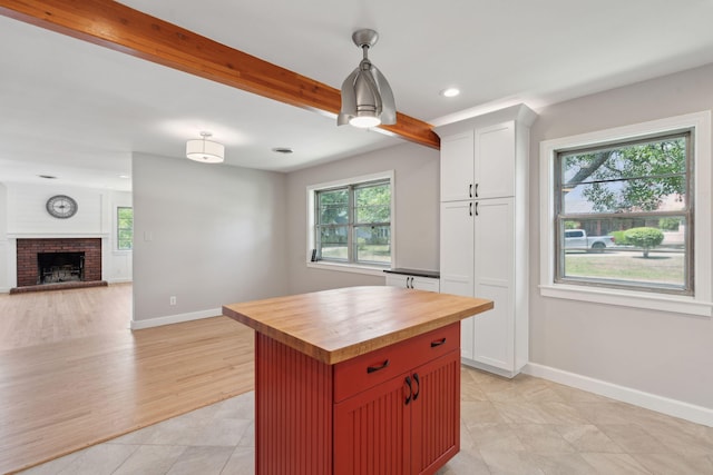 kitchen with baseboards, beam ceiling, butcher block counters, and open floor plan