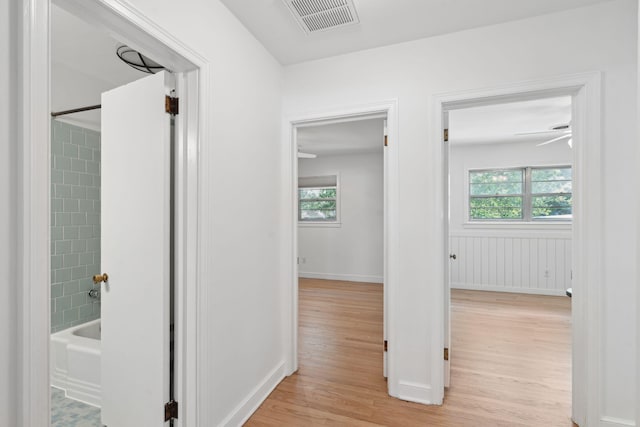 hallway with baseboards, visible vents, plenty of natural light, and light wood-style floors